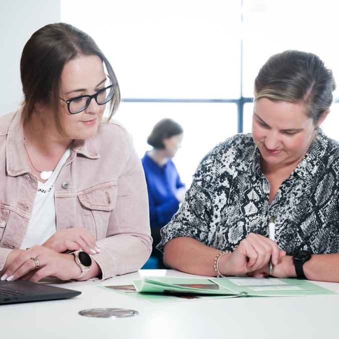 Two people working at a desk reading a worksheet